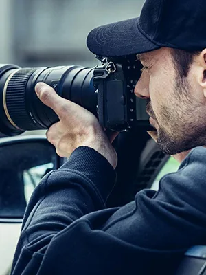 Investigatore privato che fotografa con teleobiettivo